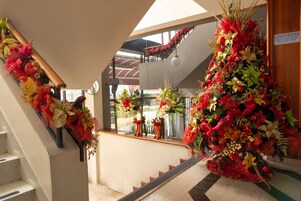 A staircase with red and gold decorations, a 'BIENVENIDO' sign, and a view of the outside through large windows.