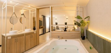 A modern bathroom with a freestanding bathtub, wooden cabinets, a vanity with a mirror, and a potted plant.