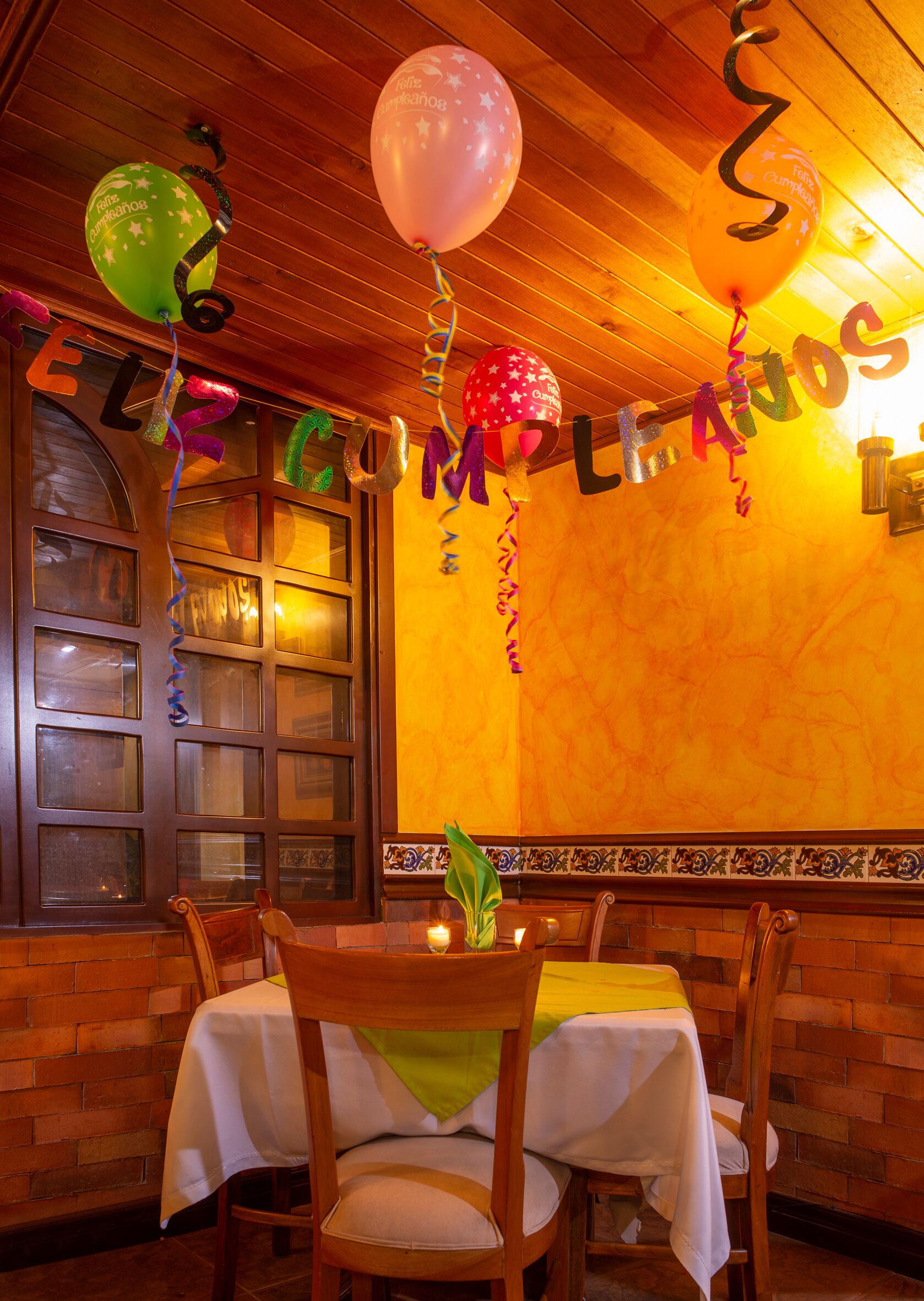 A restaurant interior with wooden ceiling, a brick wall, and a table with a white tablecloth.