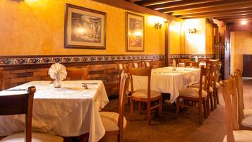 Un restaurante con varias mesas y sillas, obras de arte enmarcadas en las paredes y suelo de baldosas.