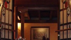 A dining area with a table set for two, a painting on the wall, and a wooden ceiling. - Hotel Príncipe (Tulua)