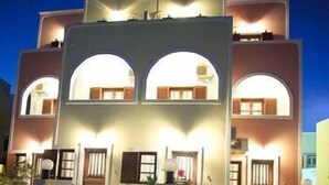 Un edificio de varios pisos con una entrada arqueada central y balcones en cada planta.
