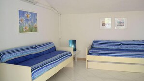 A bedroom with two beds, a small table, and two windows. - La Turistica (Capoliveri)