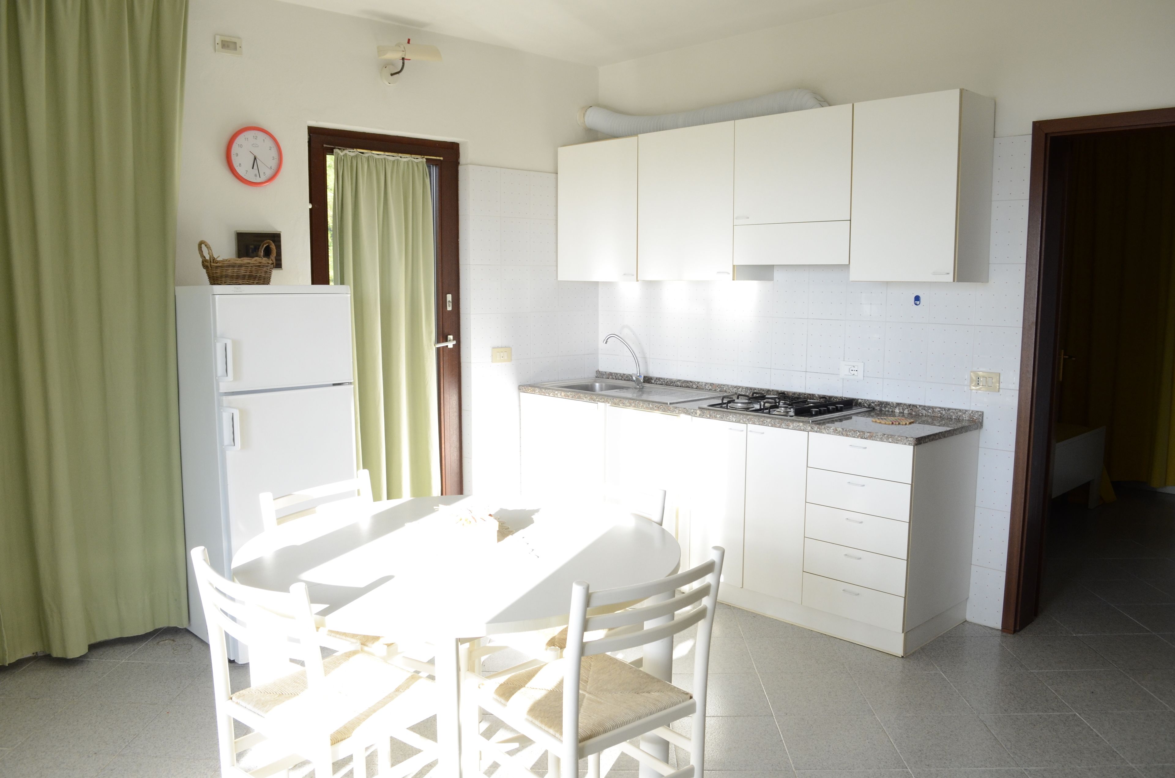 A compact kitchen with white cabinets, a sink, and a dining area with a table and chairs.