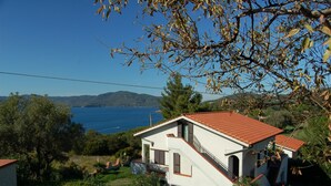 A white house with a red roof, a balcony, and a view of the sea and hills. - La Turistica (Capoliveri)