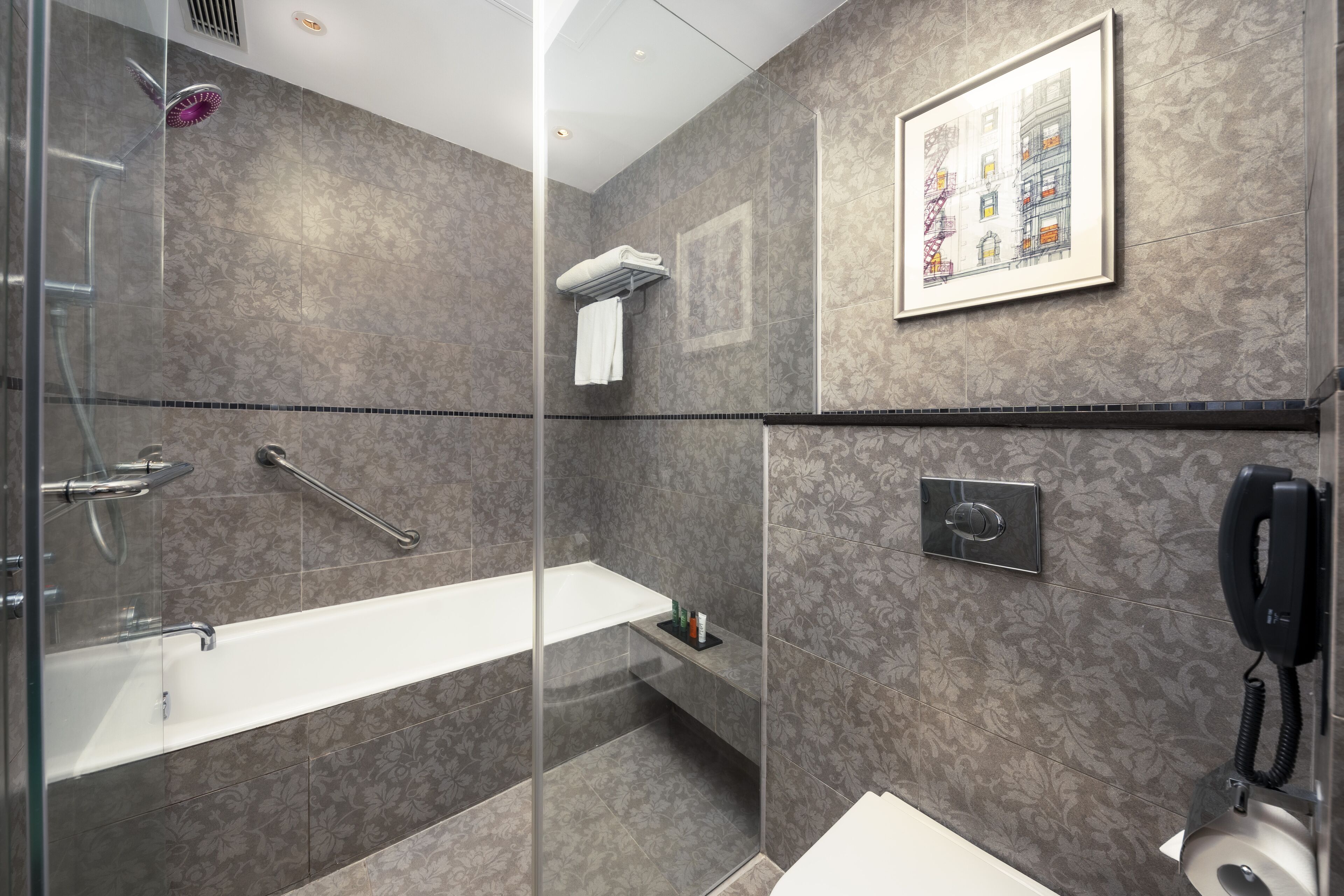 A modern bathroom with a glass-enclosed shower, a white bathtub, and a toilet.