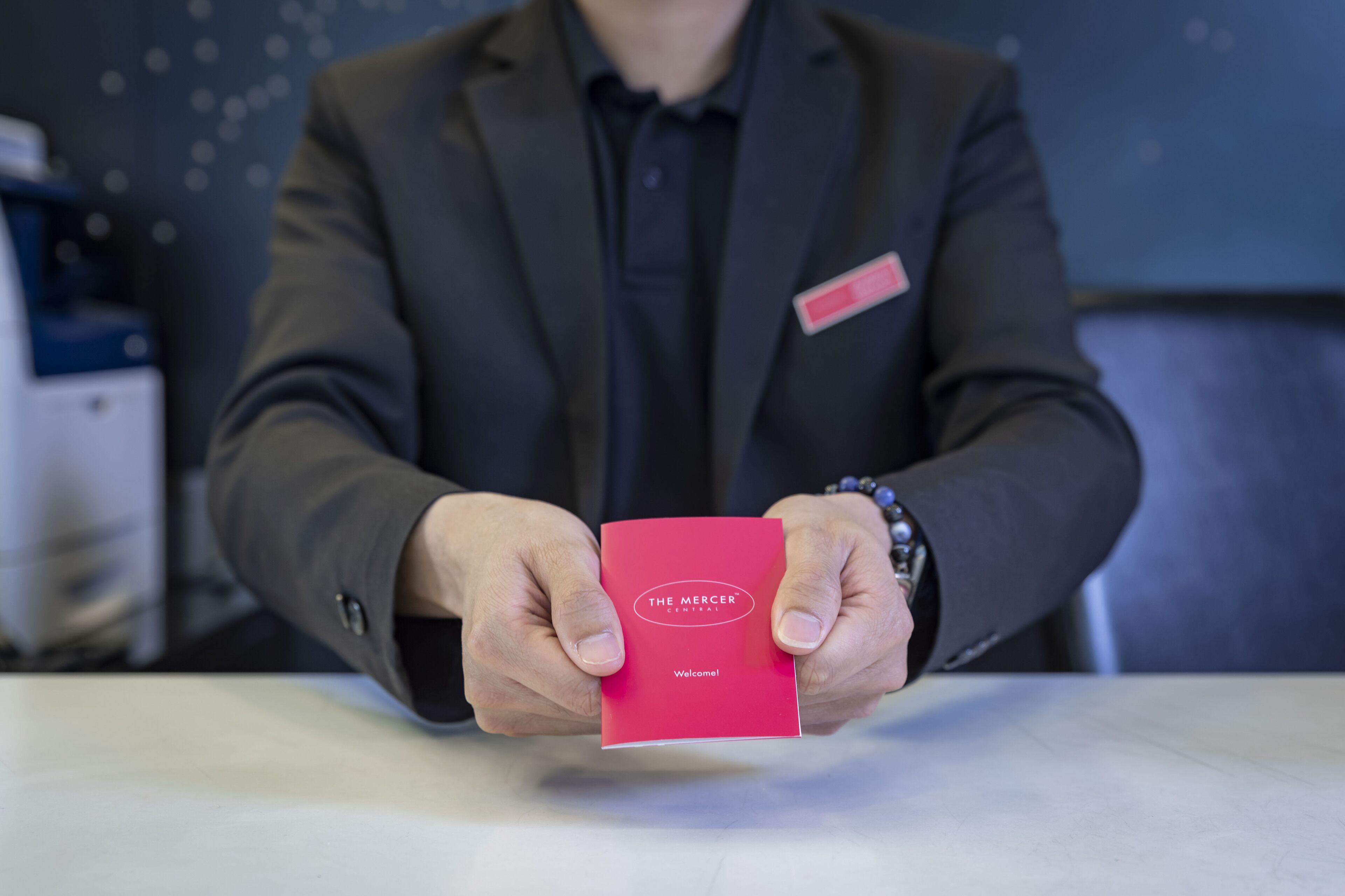 A person holding a red card with "The Mercer" on it.
