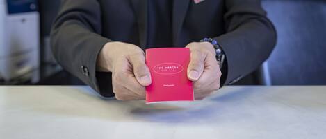A person holding a red card with "The Mercer" on it.