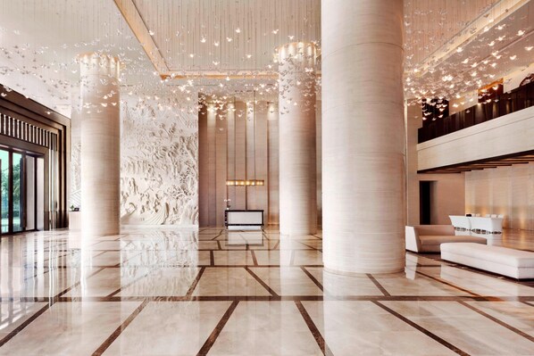A spacious lobby with large columns, a reception desk, and a seating area.