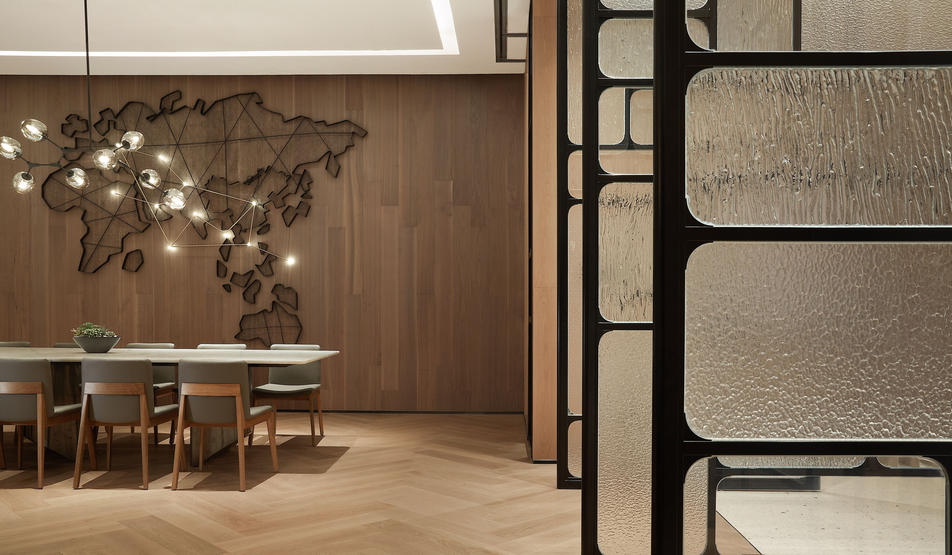 A modern dining area with a wooden wall, a world map design, and a table with chairs.