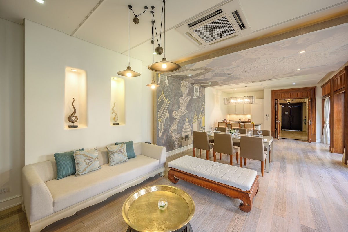 A modern living room with a sofa, a bench, and a dining area with chairs and a table.