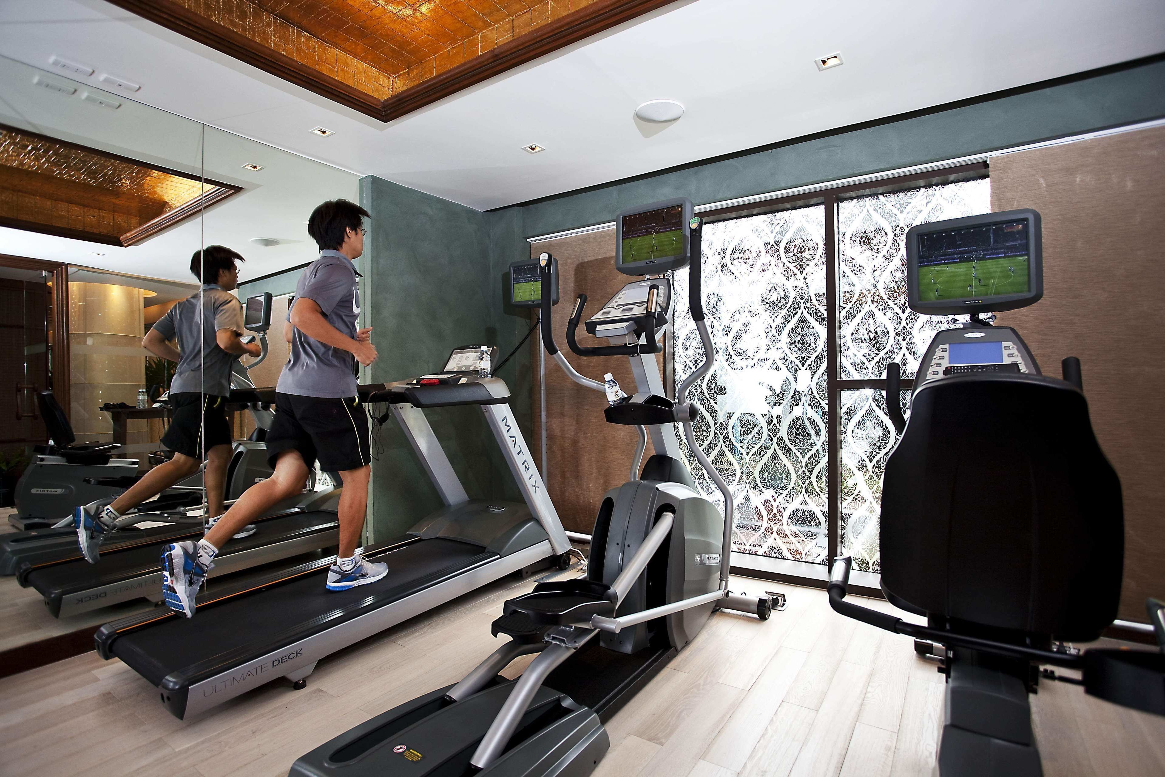 Un gimnasio con cintas de correr, elípticas y un espejo grande.