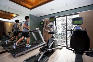 Un gimnasio con cintas de correr, elípticas y un espejo grande.