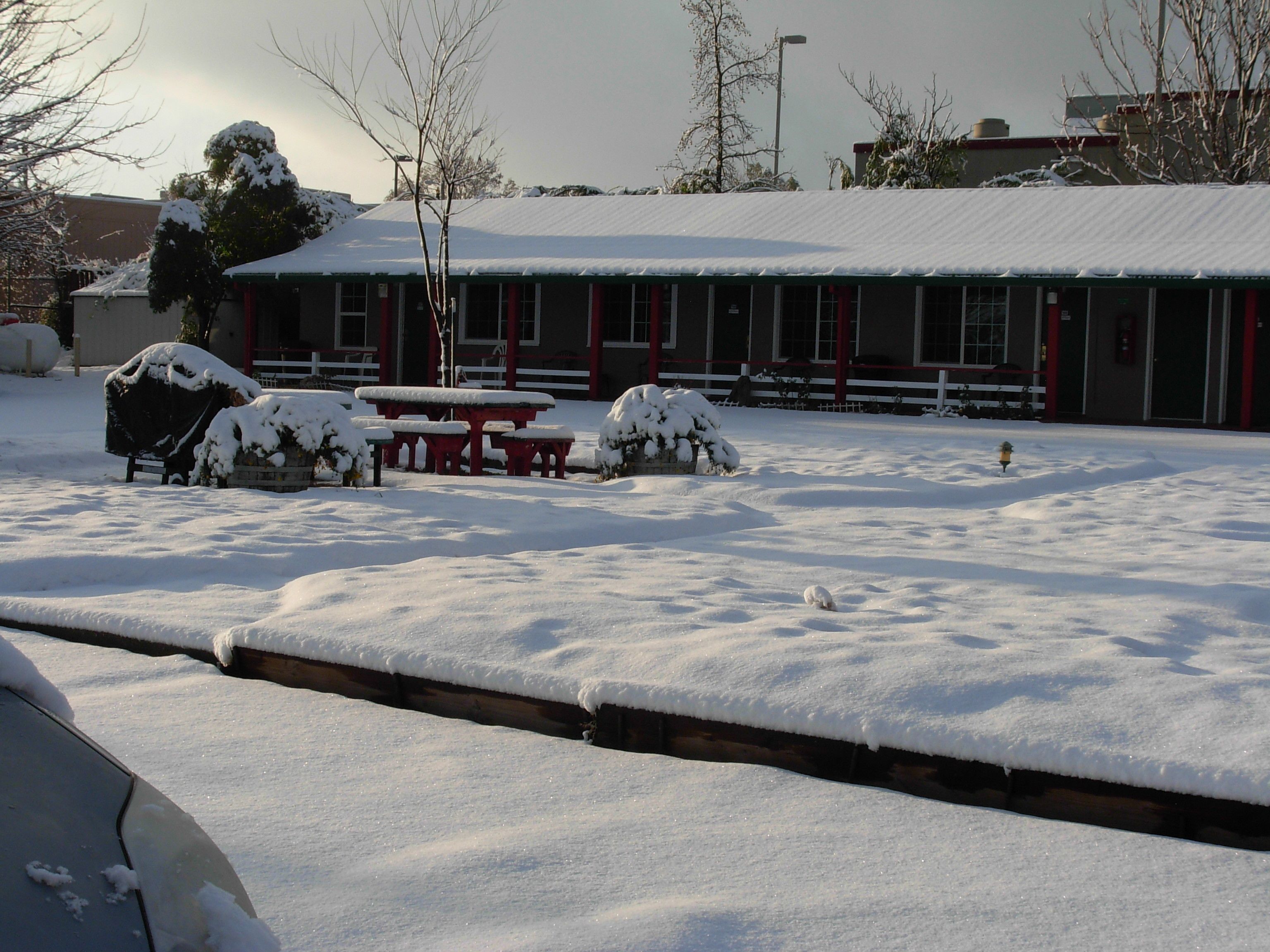 A building with a snow-covered roof and picnic tables.