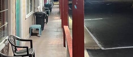 A motel corridor with rows of single-story rooms, a covered walkway, and outdoor seating.