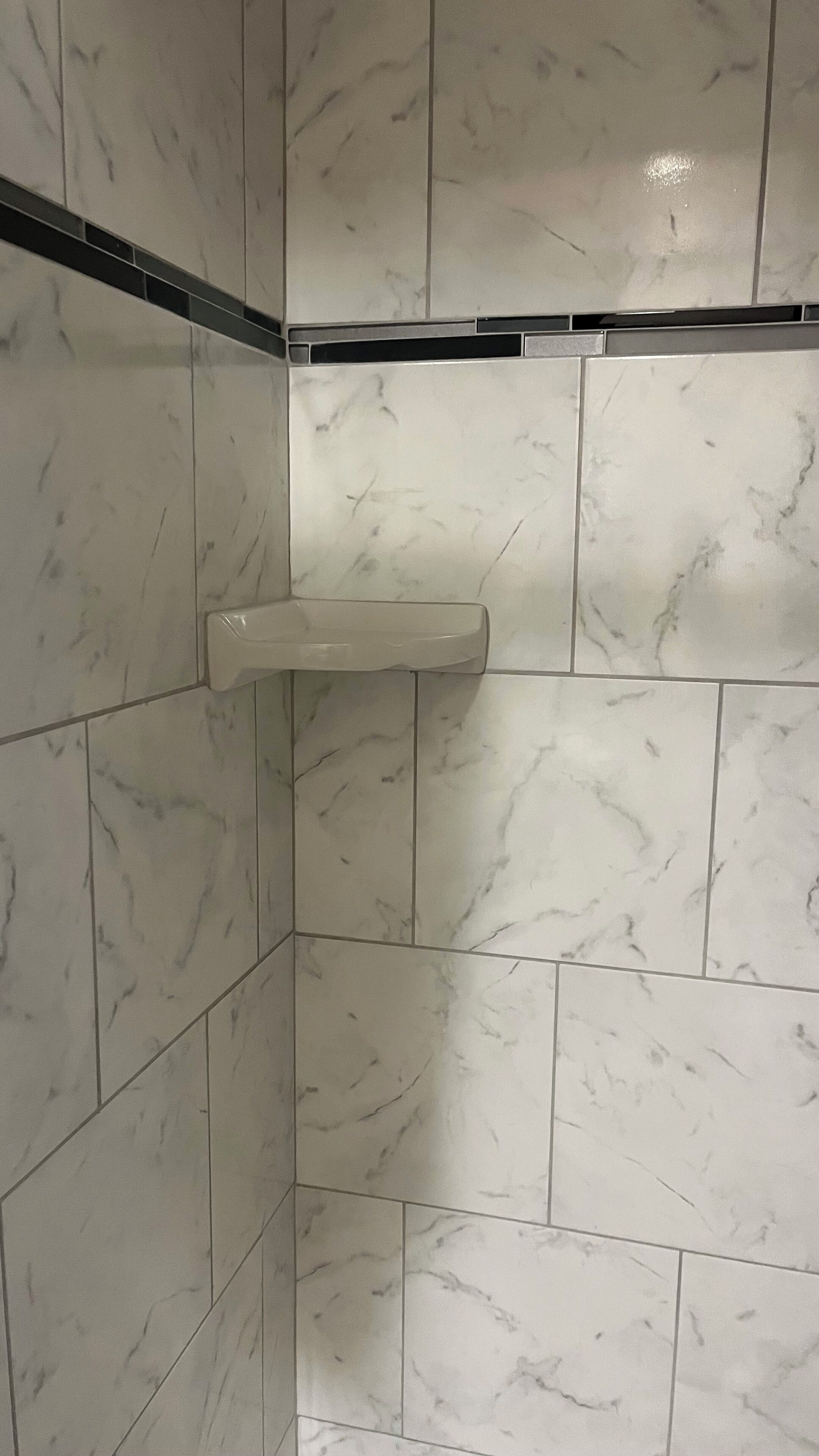 Une salle de bain avec des carreaux de marbre blanc et un porte-serviettes blanc.
