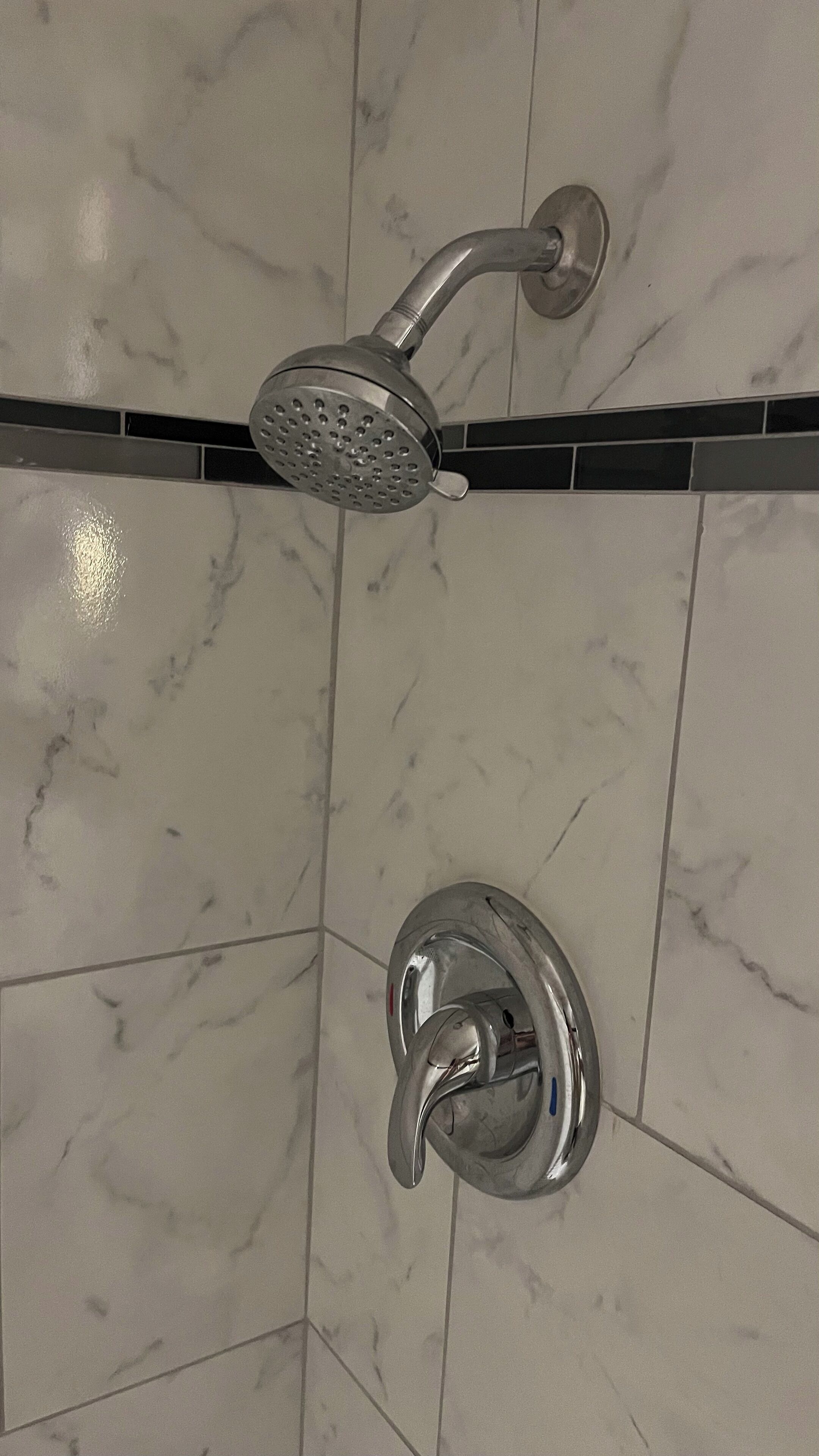 Een badkamer met douchekop en kraan op een betegelde muur.