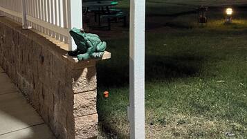 A white entrance sign with an arrow pointing right, a street lamp, and a white picket fence.