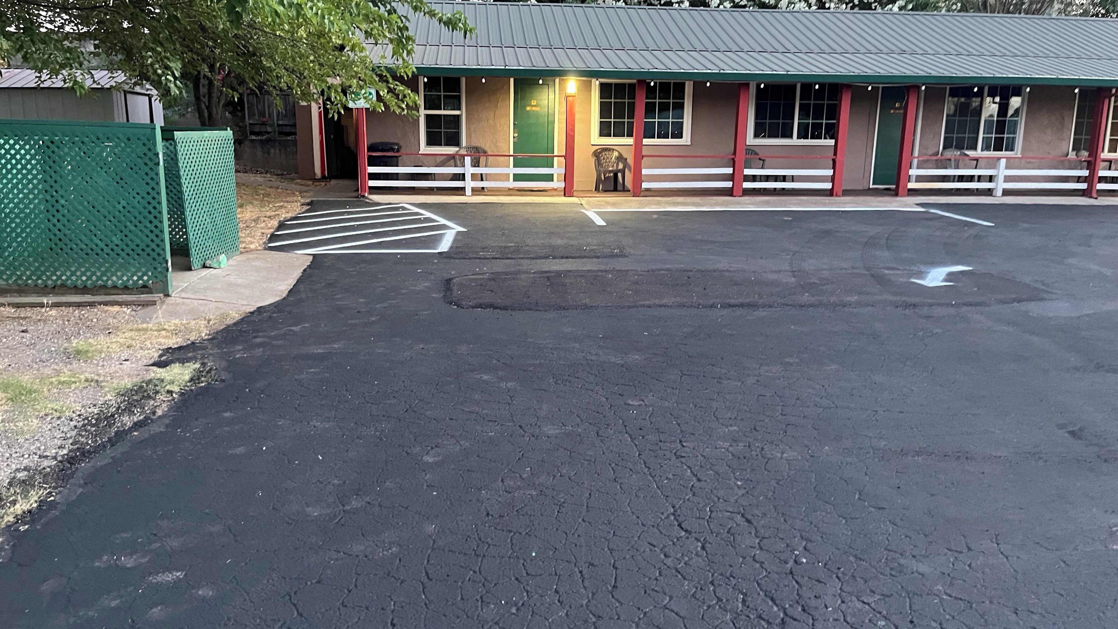 A parking lot with a building that has a green door and windows.