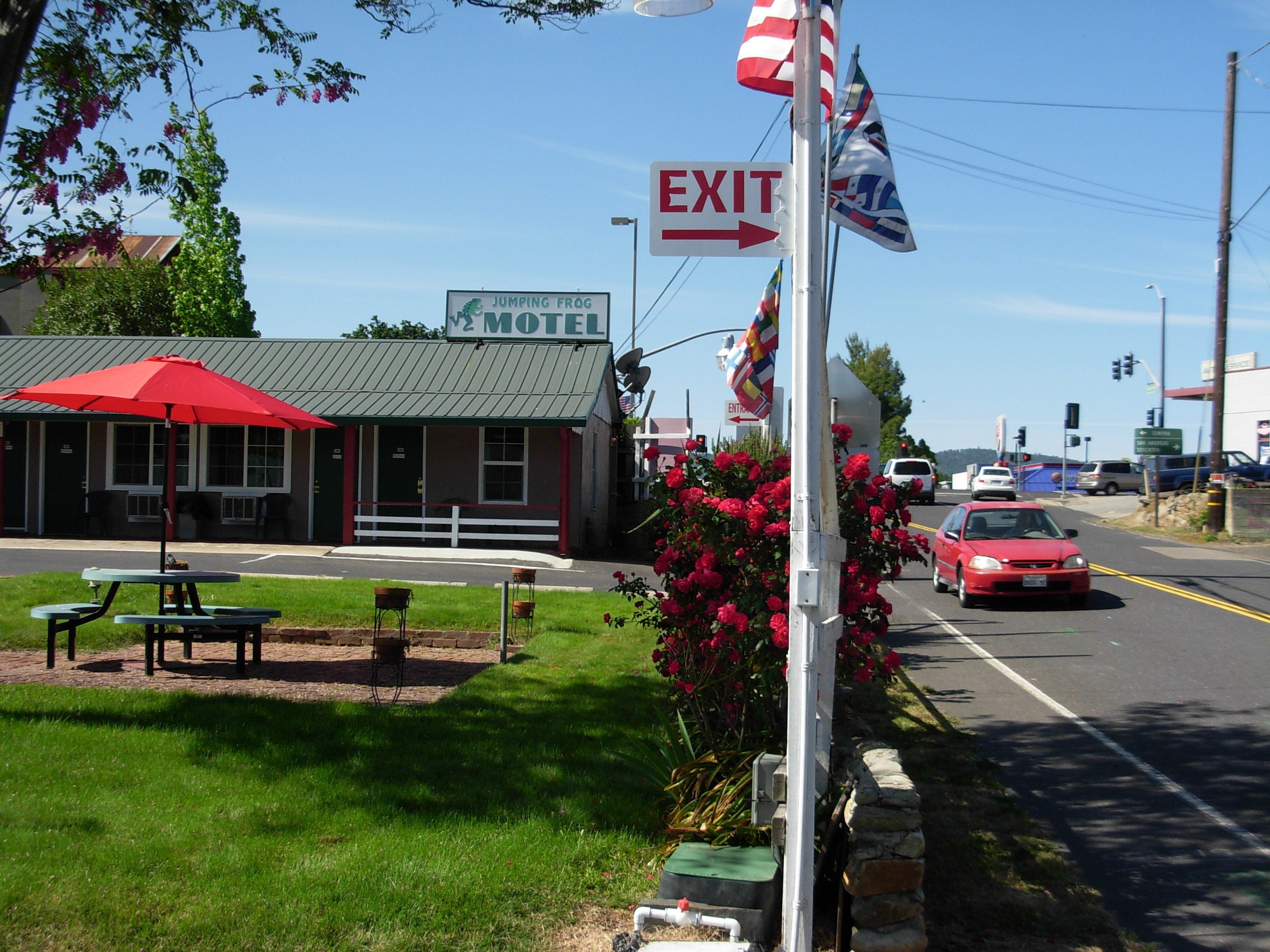Un motel avec une enseigne verte, un parasol rouge et une table de pique-nique.