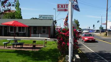 Un motel avec une enseigne verte, un parasol rouge et une table de pique-nique.