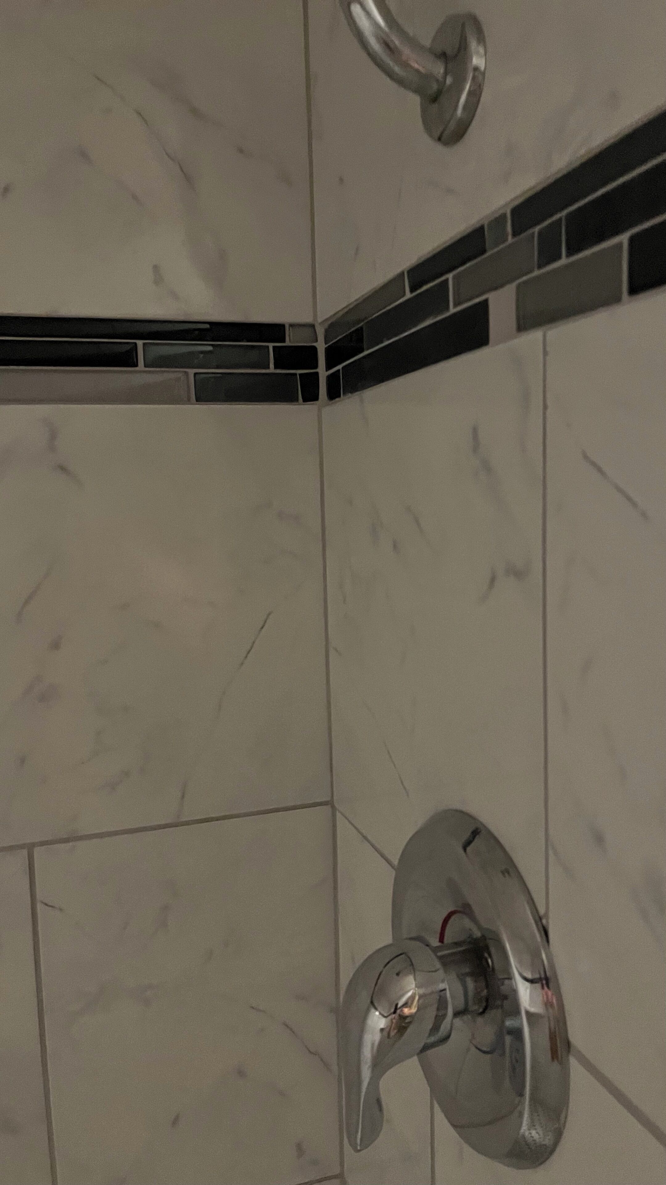 Esquina de un baño con un cabezal de ducha y un grifo empotrado en la pared.