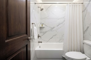 A bathroom with a bathtub, toilet, and shower curtain.