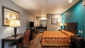 Une chambre d’hôtel comprenant un lit, un bureau, une chaise, une télévision et une salle de bain.