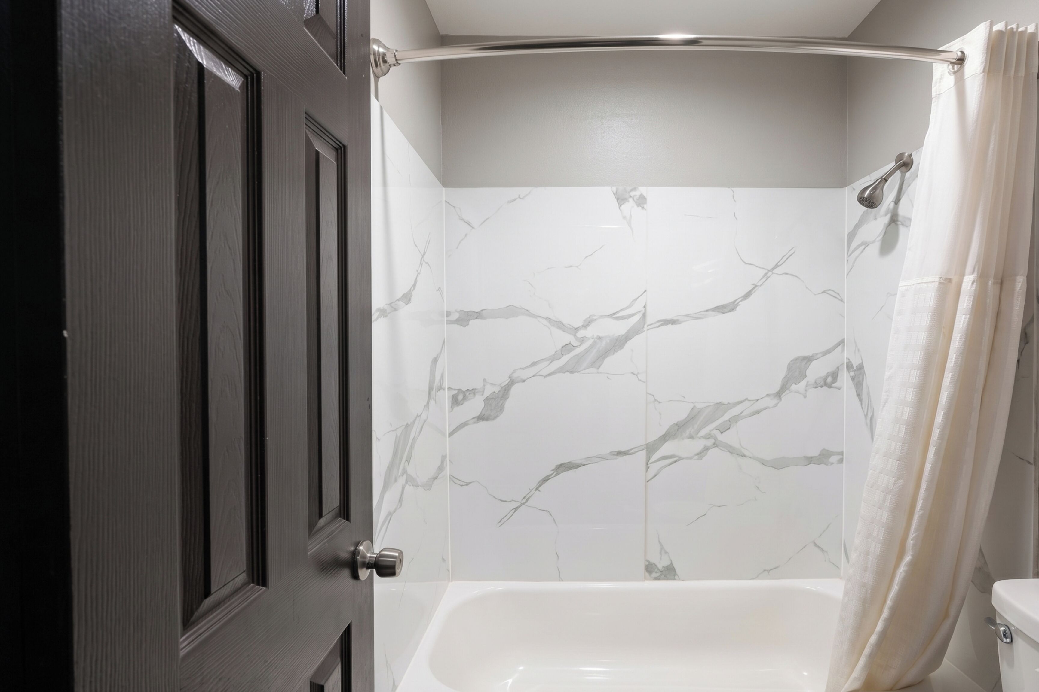 A bathroom with a shower, a toilet, and a door.