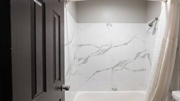 A bathroom with a shower, a toilet, and a door.