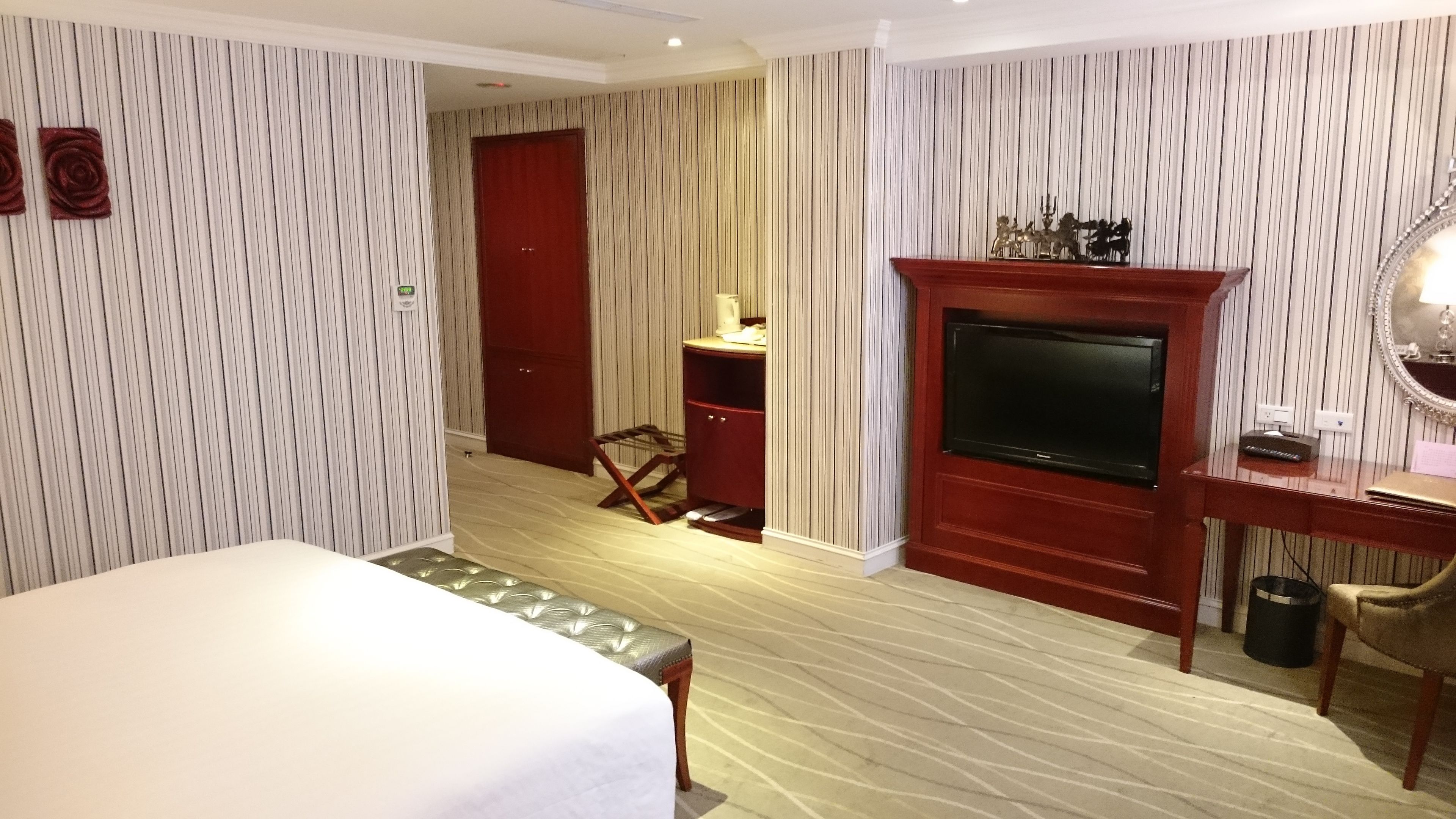 Une chambre d’hôtel avec un lit, une télévision, un bureau et un miroir.