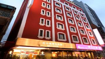 A multi-story hotel with a red facade and white window frames. The hotel's name is displayed in both English and Chinese.