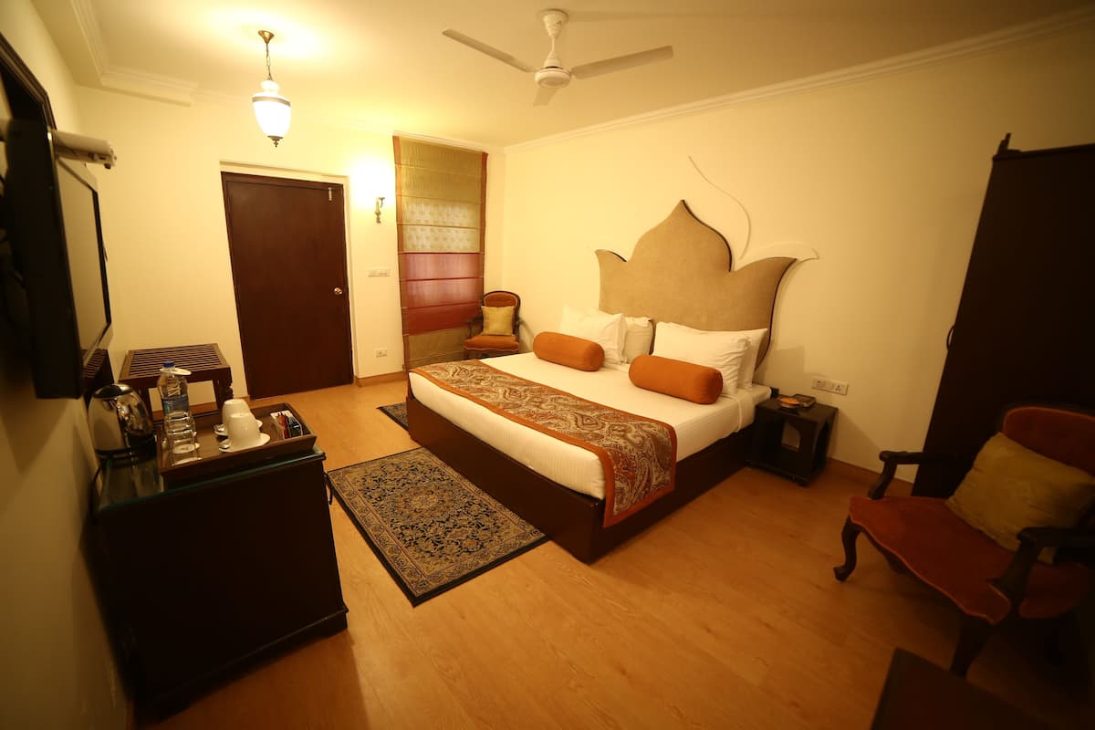 A bedroom with a bed, bedside tables, a chair, a desk, a ceiling fan, and a door.