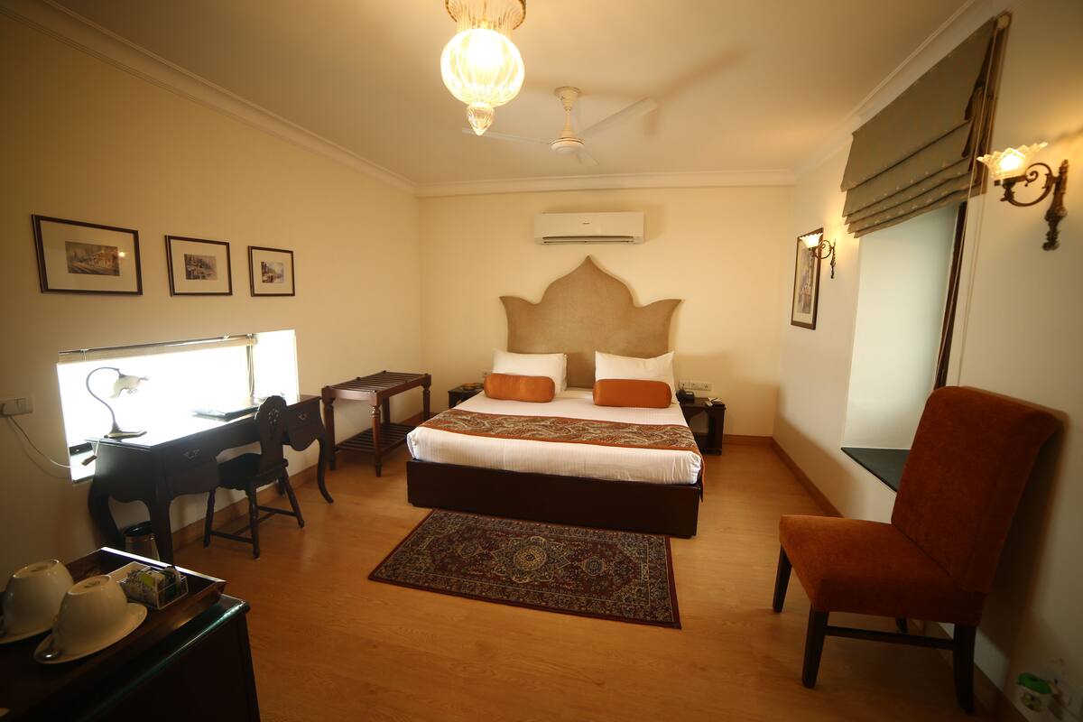 A bedroom with a bed, desk, chair, and a large window.