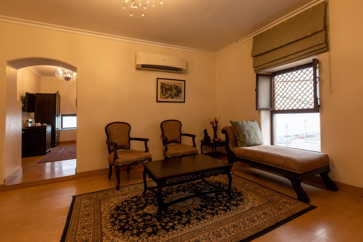A living room with a sofa, two armchairs, a coffee table, a patterned rug, and a window with a view.