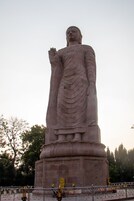 A large statue with a raised hand, surrounded by a fenced area with banners.