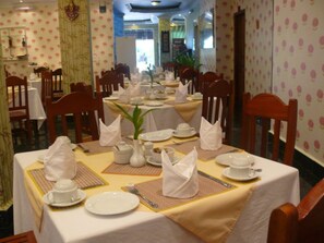 A dining area with tables set for service, chairs, and a decorative plant centerpiece. - Parklane Hotel (Siem Reap)