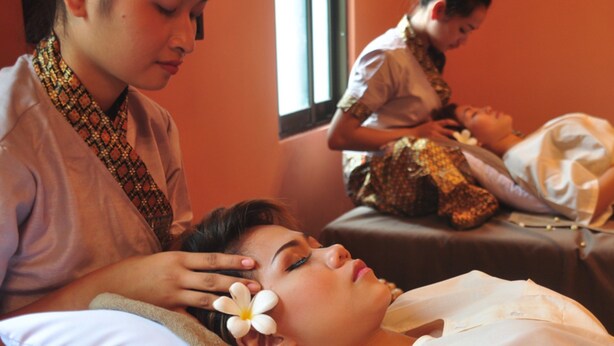 A massage therapy session in a room with two massage tables, one occupied by a client and another by a therapist. - Parklane Hotel (Siem Reap)
