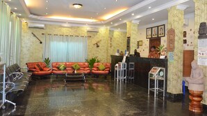 A hotel lobby with leather sofas, a reception desk, and a statue. - Parklane Hotel (Siem Reap)
