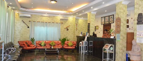 Un hall d’hôtel avec des canapés en cuir, un comptoir d’accueil et une statue.