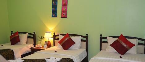 Une chambre d’hôtel avec deux lits, chacun agrémenté d’un oreiller rouge, de draps blancs et d’une décoration murale au-dessus.