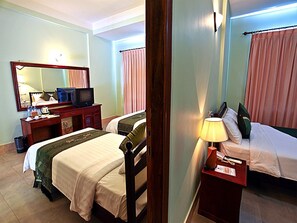 Habitación de hotel con dos camas, un escritorio, televisión, espejo y lámpara.