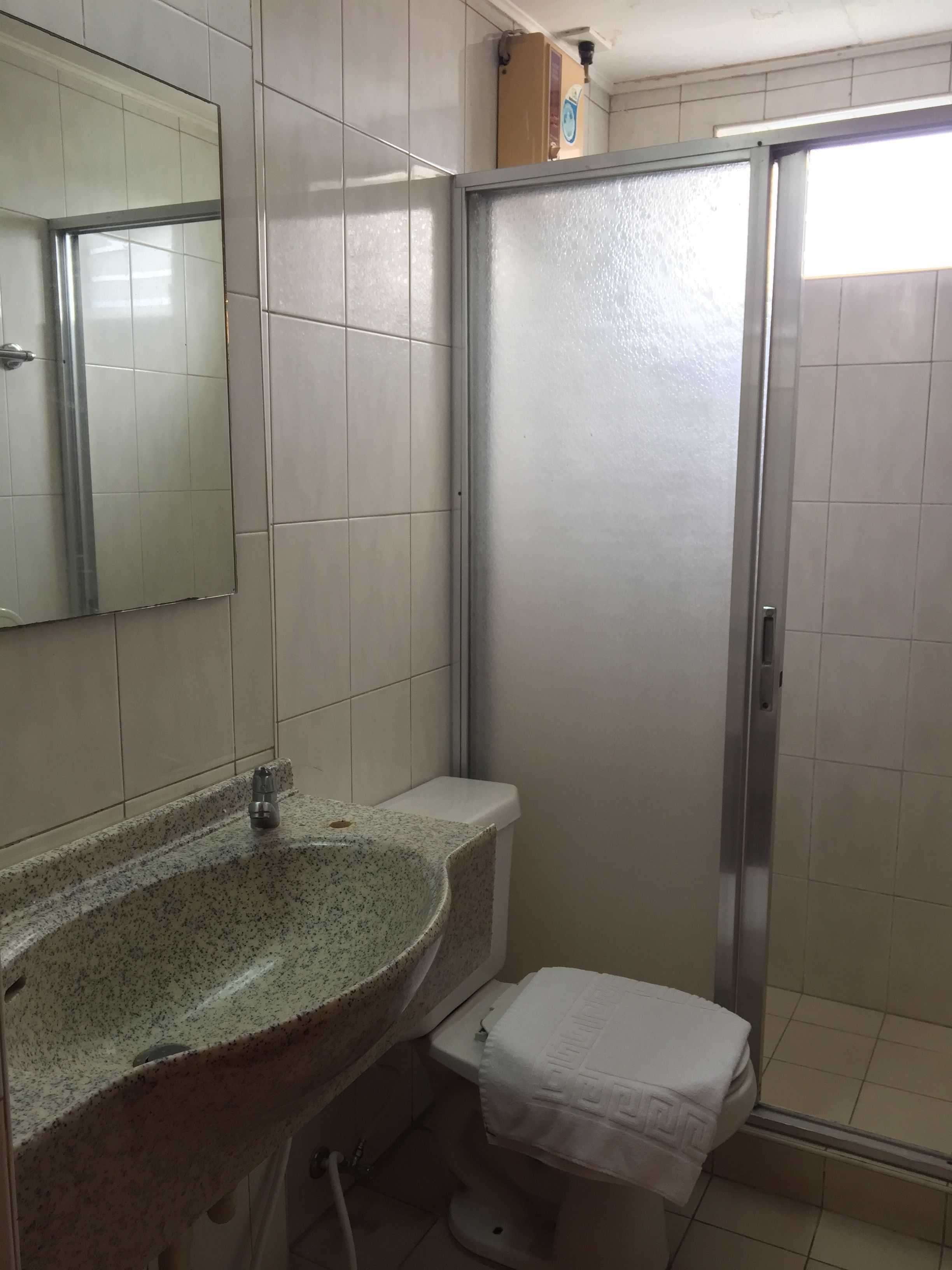 A bathroom with a granite sink, a toilet, and a shower stall.