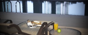 A poolside table with a magazine, a glass of orange juice, and an apple. - V Hotel Lavender (Singapore)
