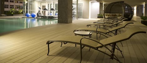 Un espace aménagé au bord de la piscine, avec des chaises longues et du matériel d’exercice.