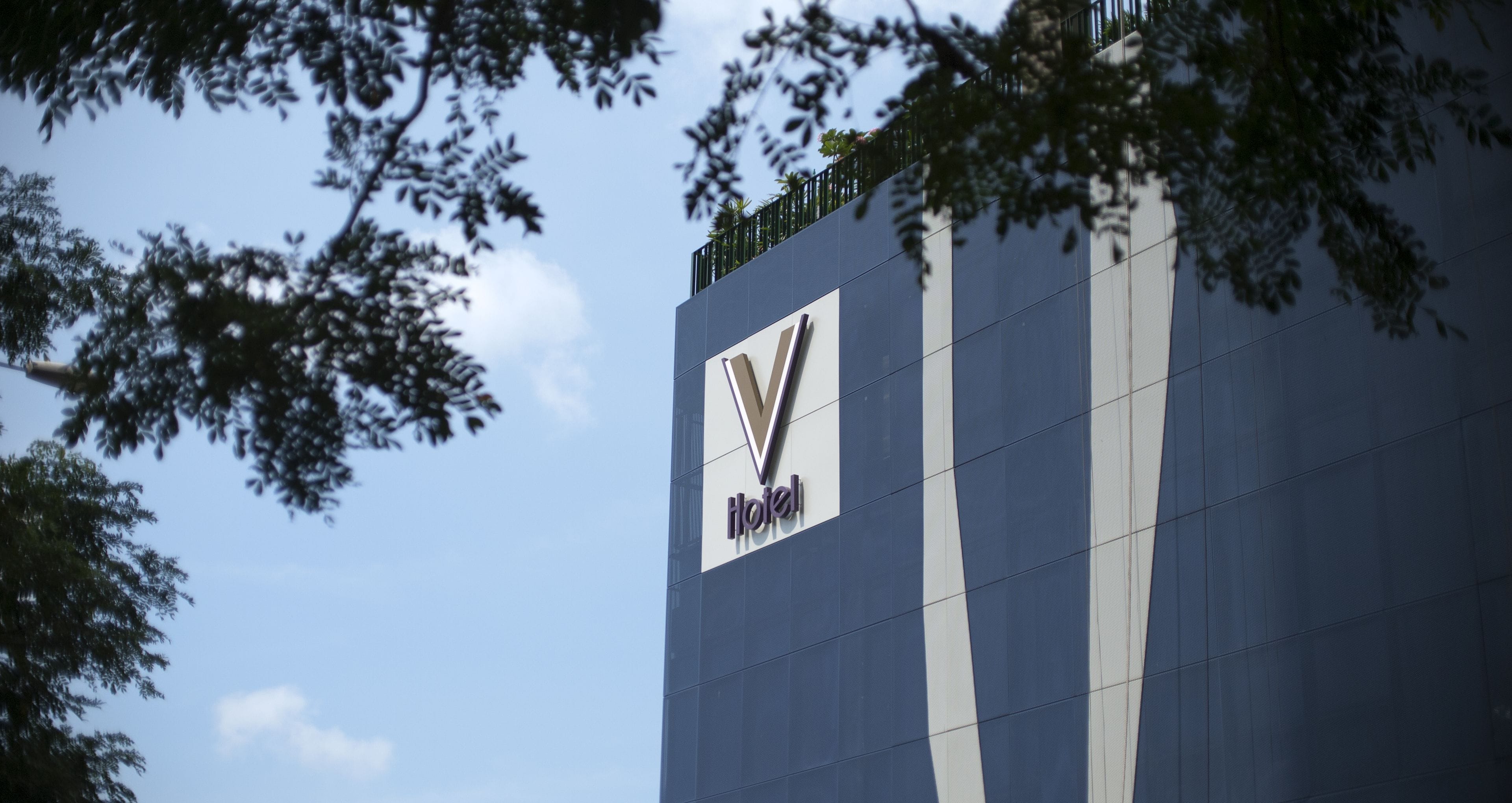 A hotel sign with a modern design, featuring a prominent logo and the word "Hotel" on a tall building.