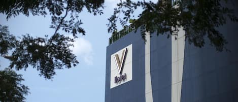 A hotel sign with a modern design, featuring a prominent logo and the word "Hotel" on a tall building.
