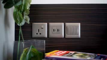 A wall-mounted electrical outlet with a switch and a USB port, a transparent vase with a green plant, and a book on a surface.