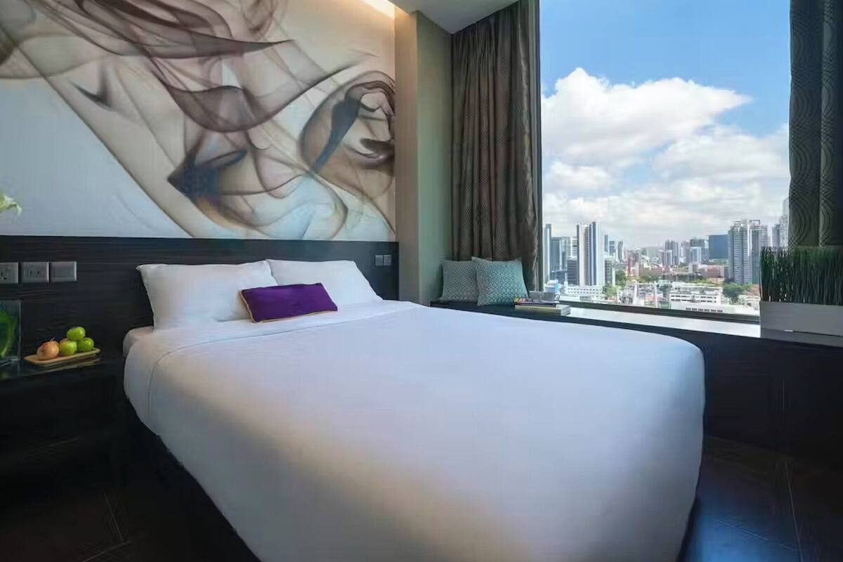 Quarto de hotel moderno com uma cama grande, vista para a cidade e uma grande pintura abstrata na parede.