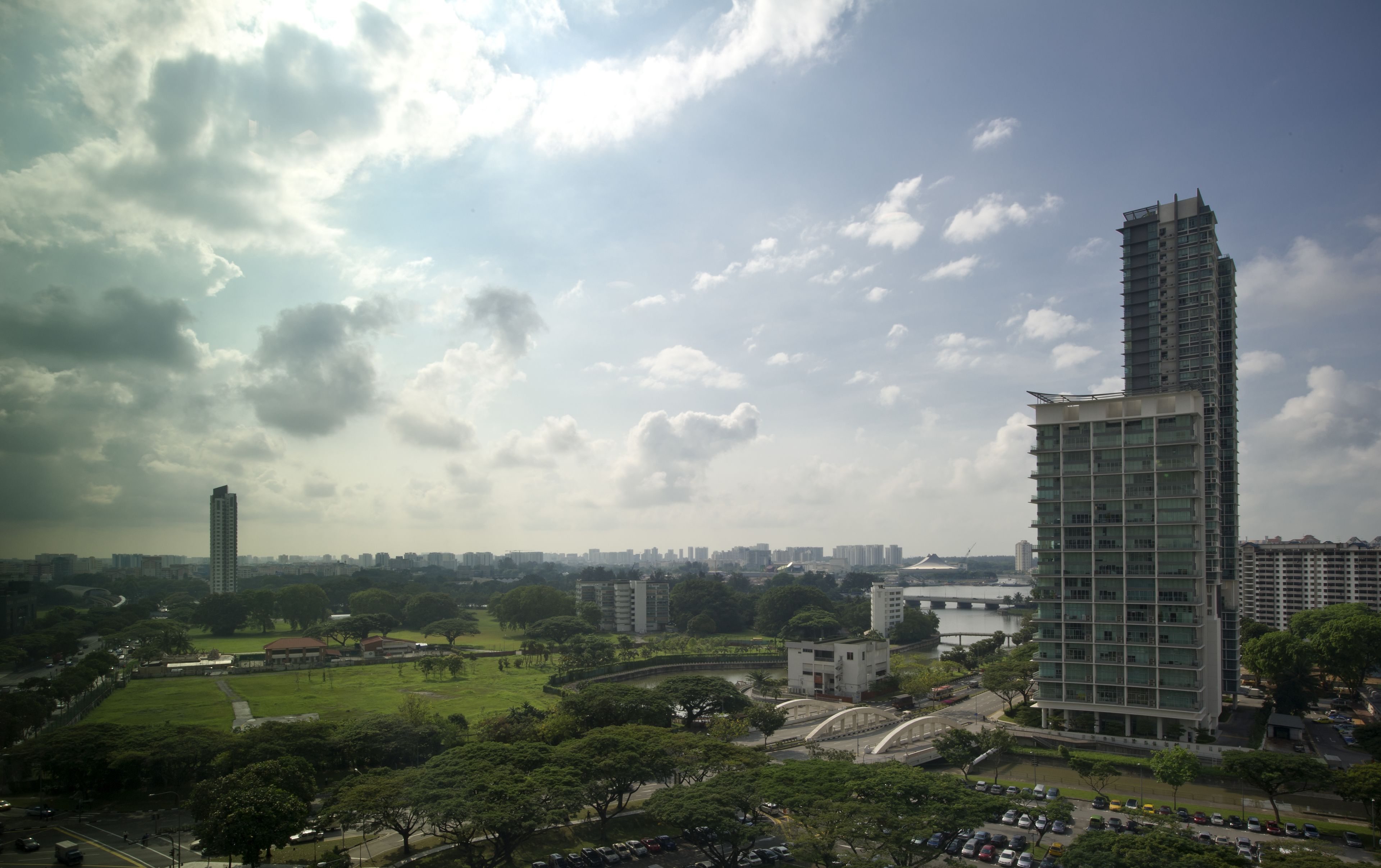 A high-rise building with a modern architectural design, surrounded by greenery and a river.